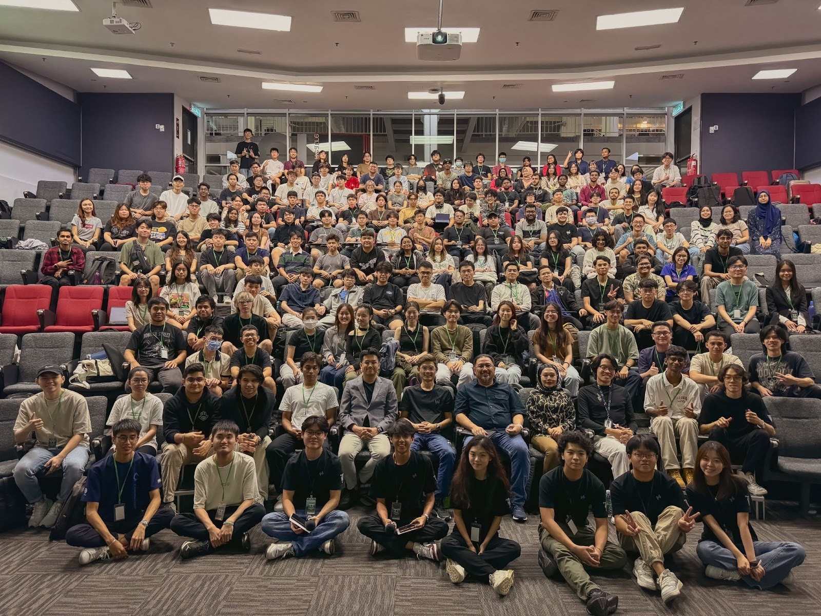 A group of happy hackathon attendees, including participants from Deriv, posing for a group photo in an auditorium